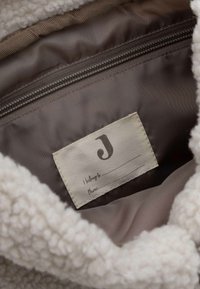 Doublure intérieure en crème moelleuse avec une poche zippée. Étiquette cousue avec une police décorative et un espace pour les détails de taille et de téléphone.