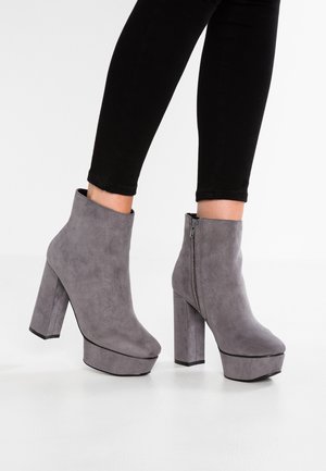 Bottes de cheville en faux suède gris avec un talon chunky et une plateforme, dotées d'une fermeture éclair sur le côté et d'une texture lisse.