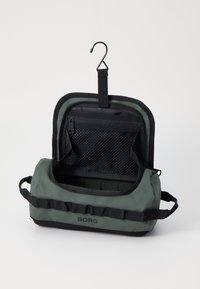 Green and black rectangular travel bag with a hook, zippered pocket, mesh compartment, and webbing straps on the sides. Smooth texture.