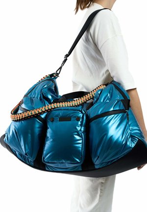 Sac rembourré bleu avec trois poches avant, base noire et une sangle tissée orange et noire. Présente une texture brillante et un design moderne.