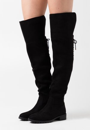 Schwarze Wildleder-Stiefel über das Knie mit flachem Absatz, seitlichem Reißverschluss und Schnürdetails hinten, mit glatter Textur und elegantem Design.