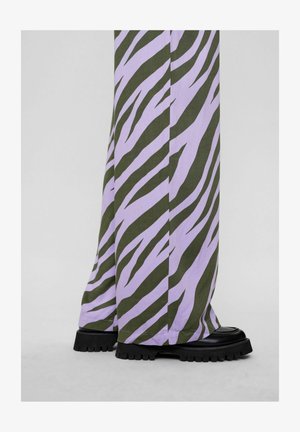 Hlače širokega kroja v barvi lavande in olivno zeleni zebri, izdelane iz teksturirane tkanine, v kombinaciji z debelimi črnimi platformnimi čevlji.