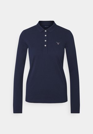 Laivastonsininen pitkähihainen poolopaita, jossa on kaulus, neljä valkoista nappia ja pieni "GANT"-logo vasemmassa rinnassa.