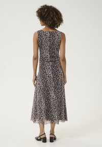 O rochie midi fără mâneci, cu imprimeu leopard în nuanțe de bej și negru, având o textură netedă și o siluetă fluidă. Sandalele cu toc negre completează ținuta.