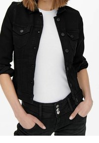 Svart denimjacka med knappstängningar och bröstfickor, bärs över en vit åtsittande skjorta; svarta jeans med dekorativa knappar vid midjan.