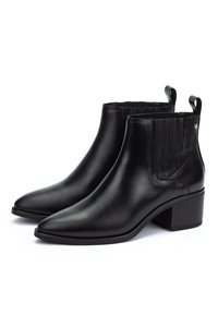 Par de botas de cuero negro hasta el tobillo con puntera afilada, tacones bajos en bloque y paneles elásticos laterales, exhibidas sobre un fondo blanco.