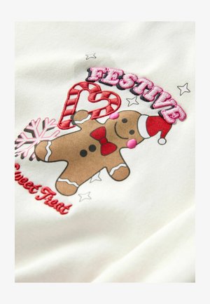 Tissu blanc avec un motif de bonhomme en pain d'épice portant un nœud rouge, un chapeau de Noël, une canne en sucre, et le texte "FESTIF" en broderie rose.