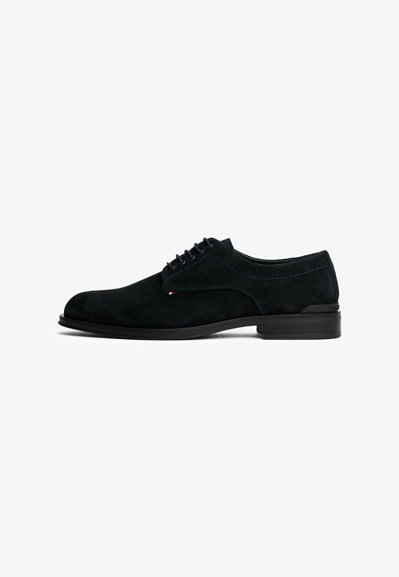 Zapatos de vestir de ante en color marino con punta redonda, 6 ojales para los cordones y costuras en contraste. Cuentan con una suela de goma negra y un branding mínimo.