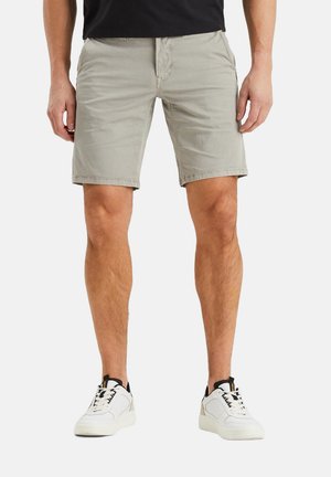 Khaki shorts with a flat front design, featuring two side pockets and an above-the-knee length, paired with white sneakers.