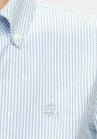 Blue and white striped button-up shirt featuring a classic collar and subtle embroidered logo on the chest. Cotton blend fabric.
