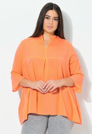 Felroze blouse met een mandarijnkraag, korte klokmouwen en een gestructureerde stof met kleine verheven stippen. Plissépunten aan de voorkant.