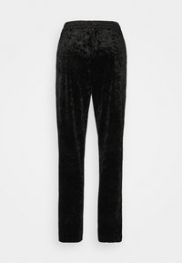 Pantalons en velours noir à jambe droite avec taille élastique, vus de dos sur un fond clair.