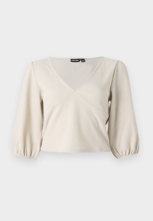 Svetle béžová blůza s výstřihem do V, texturovanou tkaninou a 3/4 rukávy s nabíranou manžetou. Má vypasovaný pas a mírně nařasené rukávy.