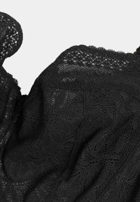 Tela de encaje negra con patrones florales y recortes intrincados. Textura suave y diseño en capas, que muestra una delicada artesanía.