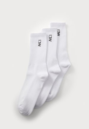 Hvite bomullssokker i en pakke med tre. Ribbete tekstur øverst med en liten svart logo trykt på hver sokk. Myk, til midten av leggen design.