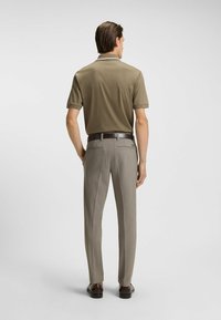 Polo shirt in olijf groen met een eenvoudige ontwerp, korte mouwen en een contrasterende kraag. Beige zakelijke broek met een tailored fit en riem.