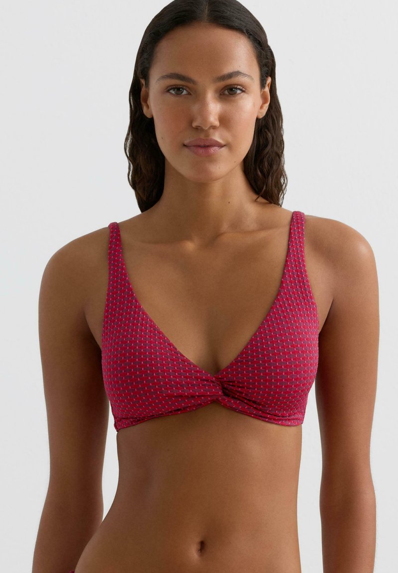 Różowy bikini top z wzorem, głębokim dekoltem w kształcie litery V i z przodem w stylu twist. Posiada cienkie ramiączka oraz teksturowaną tkaninę.