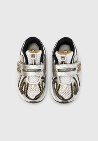 Λευκά και ασημένια παπούτσια για τρέξιμο με μαύρες λεπτομέρειες. Επάνω μέρος από δίχτυ με αυτοκόλλητο λουρί και επενδυμένο γιακά. Λαστιχένια σόλα με υφή.