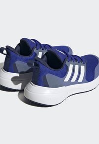 Granatowe buty sportowe z siateczkowym wykończeniem, białymi akcentami i grubą, teksturowaną podeszwą. Posiadają trzy białe paski po bokach oraz na zapiętku.
