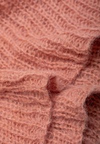 Miękki, teksturowany dzianinowy materiał w stonowanym odcieniu koralowym, z prążkowanym wzorem i puszystym wykończeniem. Idealny do tworzenia przytulnych ubrań lub akcesoriów.