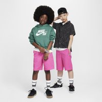 Két gyermek áll egymás mellett. Az egyik zöld Nike SB kapucnis pulcsit és rózsaszín sortot visel; a másik fekete mintás inget és szintén rózsaszín sortot, mindketten sportcipőt viselnek.