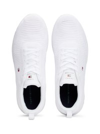Scarpe sportive bianche con parte superiore in maglia testurizzata e design con lacci. Presentano un piccolo logo con accenti rossi e blu sui lati.