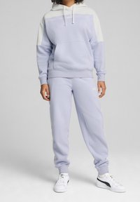 Lichtpaarse hoodie met witte accenten en logo, gecombineerd met bijpassende lichtpaarse sweatpants, beide gemaakt van zachte stof en voorzien van elastische boorden.