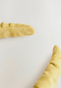 Kaks kollast nubuknahast kätist, millel on ribakujulised haardepadjad, asetatud heledale pinnale diagonaalis vastamisi.