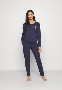 Navyblå pyjama-set bestående av en långärmad topp med rund halsringning och text fram; matchande tajta byxor med en mjuk och slät textur.