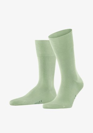 Calzini di cotone verde chiaro con polsini a costine, una trama liscia e un piccolo logo stampato in una tonalità più scura vicino alla punta.