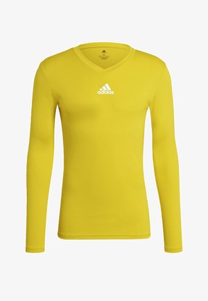 Langsleeve geel sportshirt van gladde stof. Heeft een V-hals en een wit Adidas-logo dat gecentreerd op de borst is.