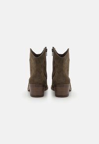 Botas de ante marrón hasta el tobillo con un tacón de bloque bajo, que cuentan con cremalleras laterales y un diseño en la parte trasera puntiaguda para una silueta elegante.