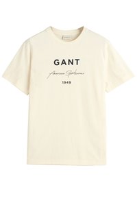 Krémové bavlněné tričko s krátkým rukávem, se černým textem: "GANT American Sportswear 1949" v tučném a kurzívním písmu.