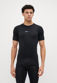 Tricou sportiv negru cu mâneci scurte, fabricat din material elastic. Prezintă un mic logo alb Nike pe piept. Design ajustat.
