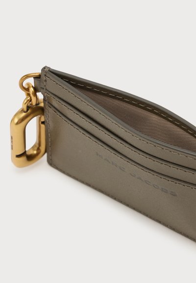 Porte-cartes en cuir gris mince avec plusieurs compartiments et un mousqueton en métal doré fixé sur le côté.