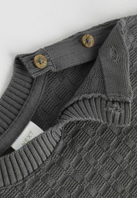 Gray knitted sweater with a textured, diamond pattern. Features a ribbed collar and two golden buttons on the neck. Soft fabric.