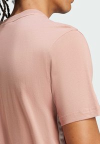 Camiseta de manga corta color rosa claro, hecha de algodón suave, con un diseño sencillo, cuello redondo clásico y costuras laterales sutiles.