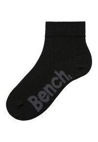 Calcetín negro hasta el tobillo hecho de material suave; presenta un logo "Bench." en gris oscuro en el costado y un puño acanalado para un ajuste seguro.