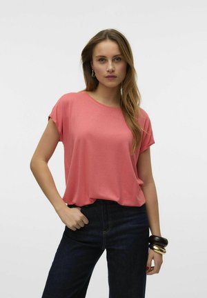 Koralfarvet T-shirt med korte ærmer, afslappet pasform, rund halsudskæring og subtil tekstur, parret med mørke denimjeans og stablede armbånd.