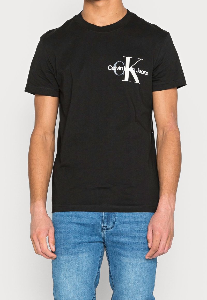 Černé bavlněné tričko s bílým logem Calvin Klein Jeans na levé straně hrudi, kulatým výstřihem a krátkými rukávy. Klasický střih.