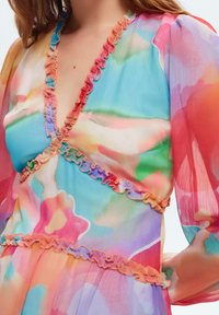 Farbenfrohes, leichtes Kleid aus transparentem Stoff. Mit tiefem V-Ausschnitt, rüschenförmigen Kanten und abstrakten Aquarellmustern in Pastellfarben.