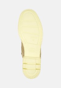 Zool van een laars met een getextureerde gele rubberen onderkant, met duidelijke ribbels en patronen, vergezeld van een bovenrand van beige suède.