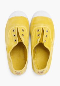 Zapatillas de lona amarillas con punteras de goma blanca, seis ojales y forro de tela texturizada. Incluye un parche con el logotipo en el talón.
