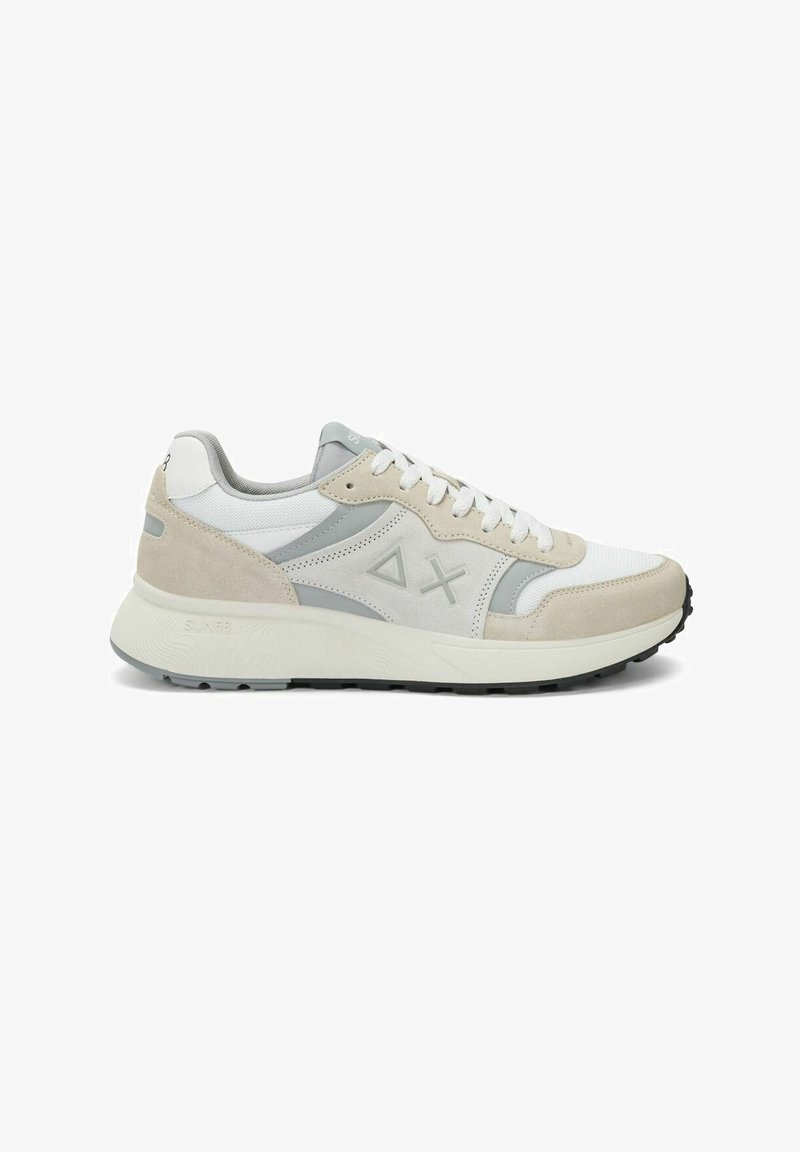 Zapatilla blanca y beige con detalles en gris, paneles de ante y malla, suela acolchada, diseño con cordones y formas en relieve de triángulo y cruz en el lateral.