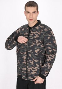 Camo bomberjakke i nuancer af grøn, sort og beige. Har lynlås foran, ribbede mansjetter og to sidelommer. Glat, syntetisk materiale.