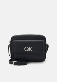 Schwarze Leder-Crossbody-Tasche mit silbernem Logo, rechteckiger Form, einer einzigen Frontklapptasche und verstellbarem Trageriemen. Glatte Textur, minimalistisches Design.