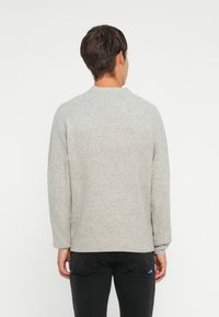 Gray knit sweater with long sleeves and a round neckline. Features a ribbed hem and cuffs, showcasing a soft texture and casual design.