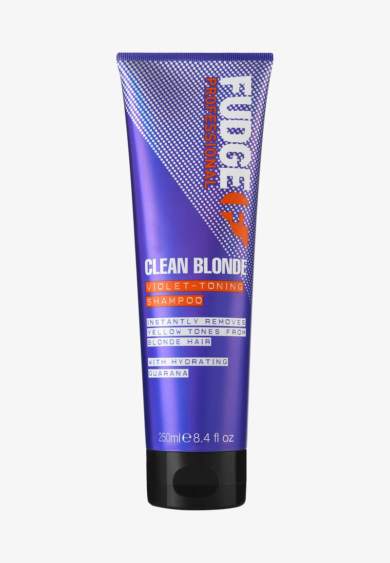 Violet-toning sjampo i en lilla tube med hvit og oransje tekst. Størrelse 250ml. Har en svart hette og geometriske designelementer.