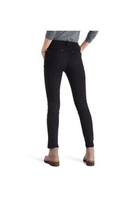 Black skinny jeans with a high waist, made of stretchy fabric. Features two back pockets and a smooth finish. Worn with tan ankle boots.