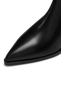 Zwarte leren stilettohak met een spitse neus, gladde textuur en een minimalistisch ontwerp. De slanke figuur benadrukt de moderne uitstraling.
